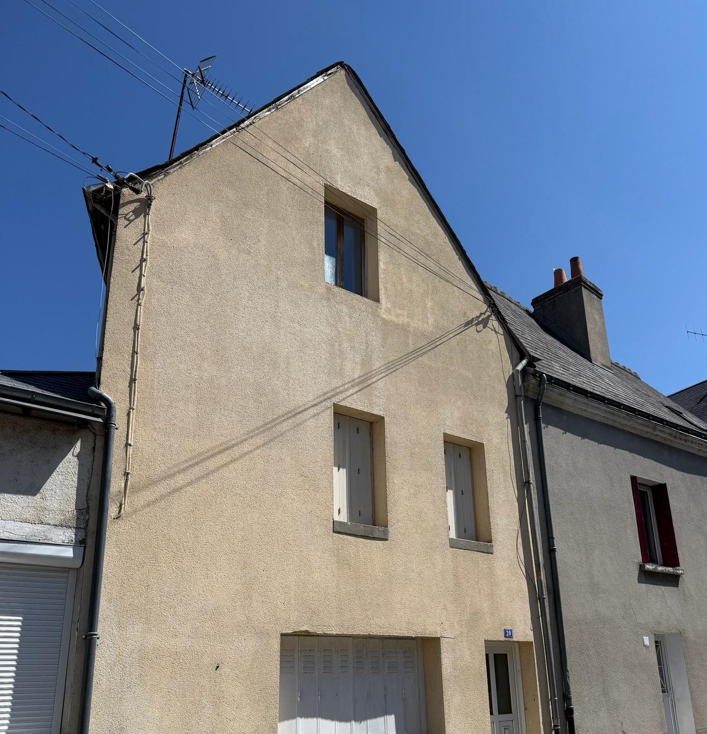 Pignon de maison de bourg après ravalement : enduit uniforme et rive de toit reprise